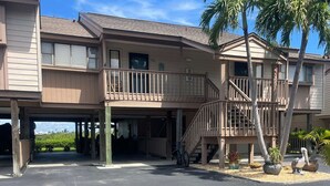 A multi-story hotel with a covered parking area and a balcony with a railing. - Captains Harbor Island Hide Away (Bokeelia)