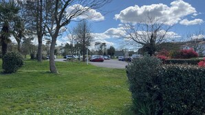 Ein Parkplatz mit Autos, Bäumen und blauem Himmel.