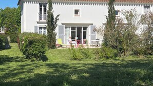 Ein zweistöckiges Haus mit Ziegeldach, einem Balkon und einer Terrasse mit Gartenmöbeln.