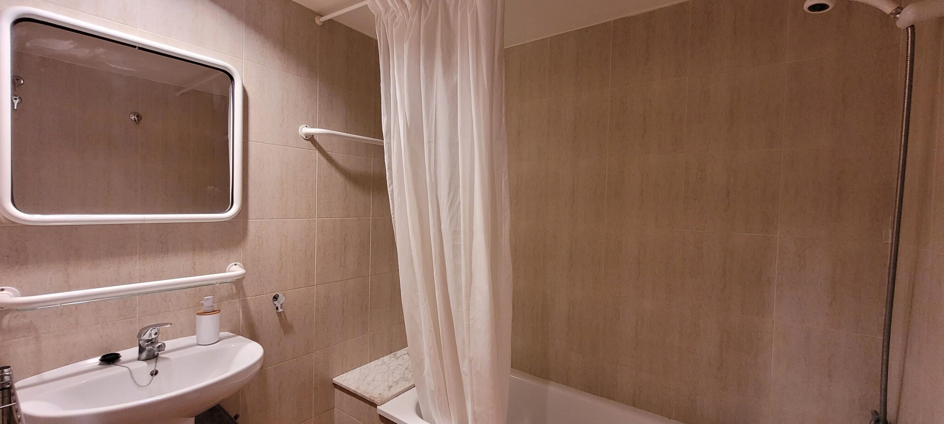 A bathroom with a sink, mirror, and shower curtain.
