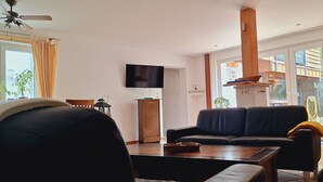 Un salon moderne avec un canapé, une table basse et un téléviseur à écran plat fixé au mur.