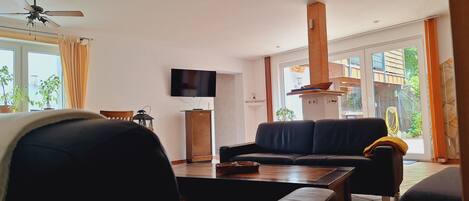 A modern living room with a sofa, a coffee table, and a flat-screen TV mounted on the wall.