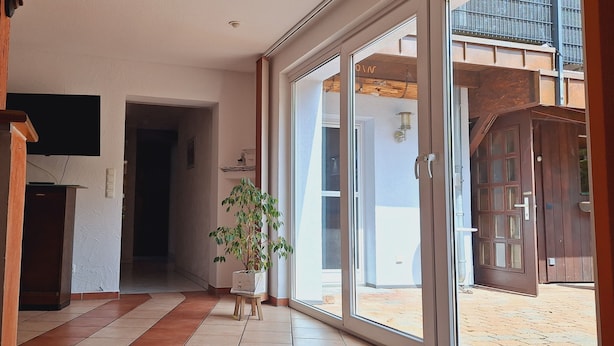 Une porte ouverte donnant sur un balcon d’où l’on peut admirer un immeuble.
