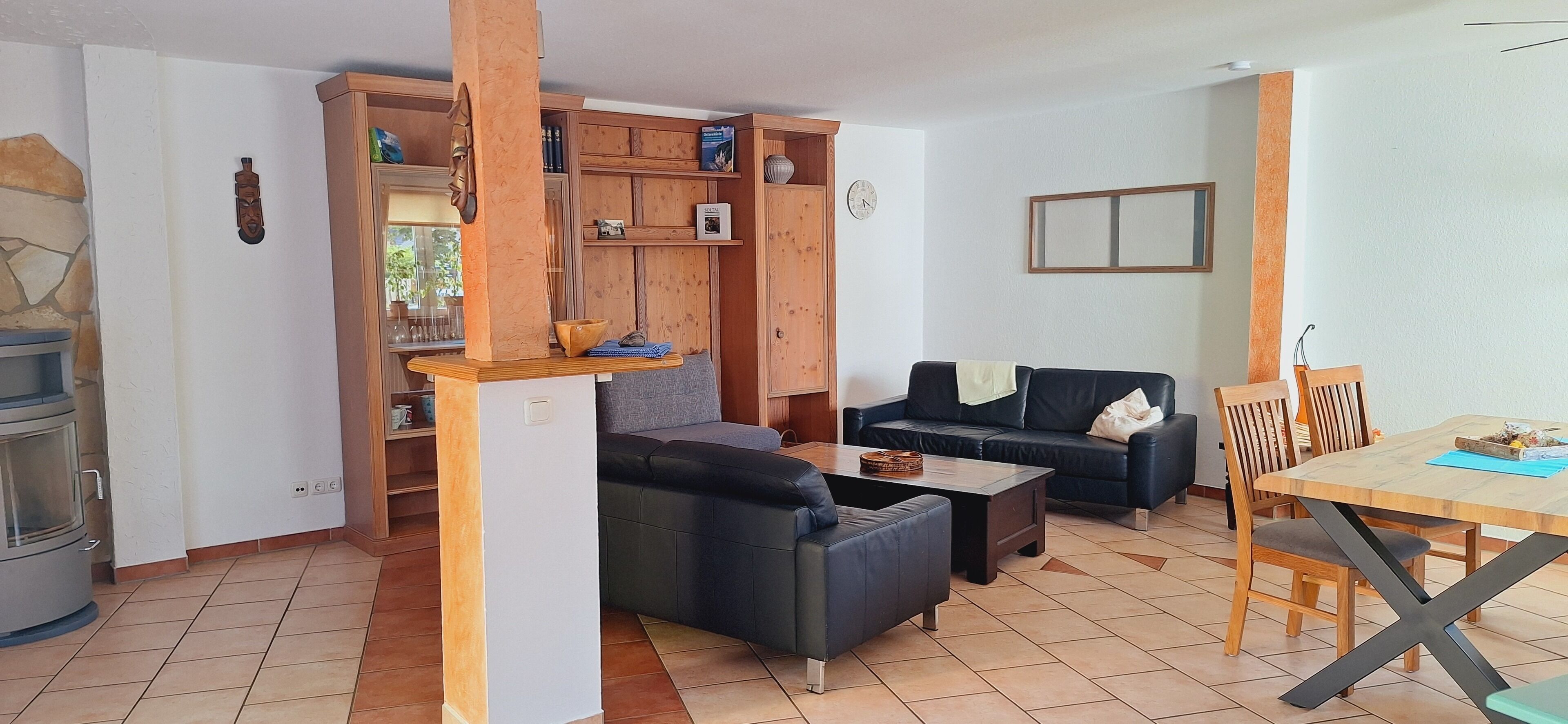Un espace de vie compact comprenant un coin cuisine, un canapé, une table à manger et un meuble en bois.