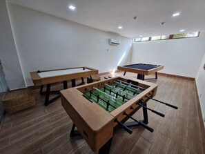 Ein Raum mit Tischfußball, Billardtisch und Poolbillard.