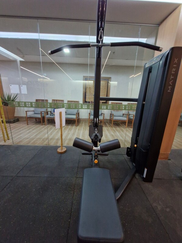 Un gimnasio con equipo de ejercicio, incluyendo una banca y una máquina de poleas.