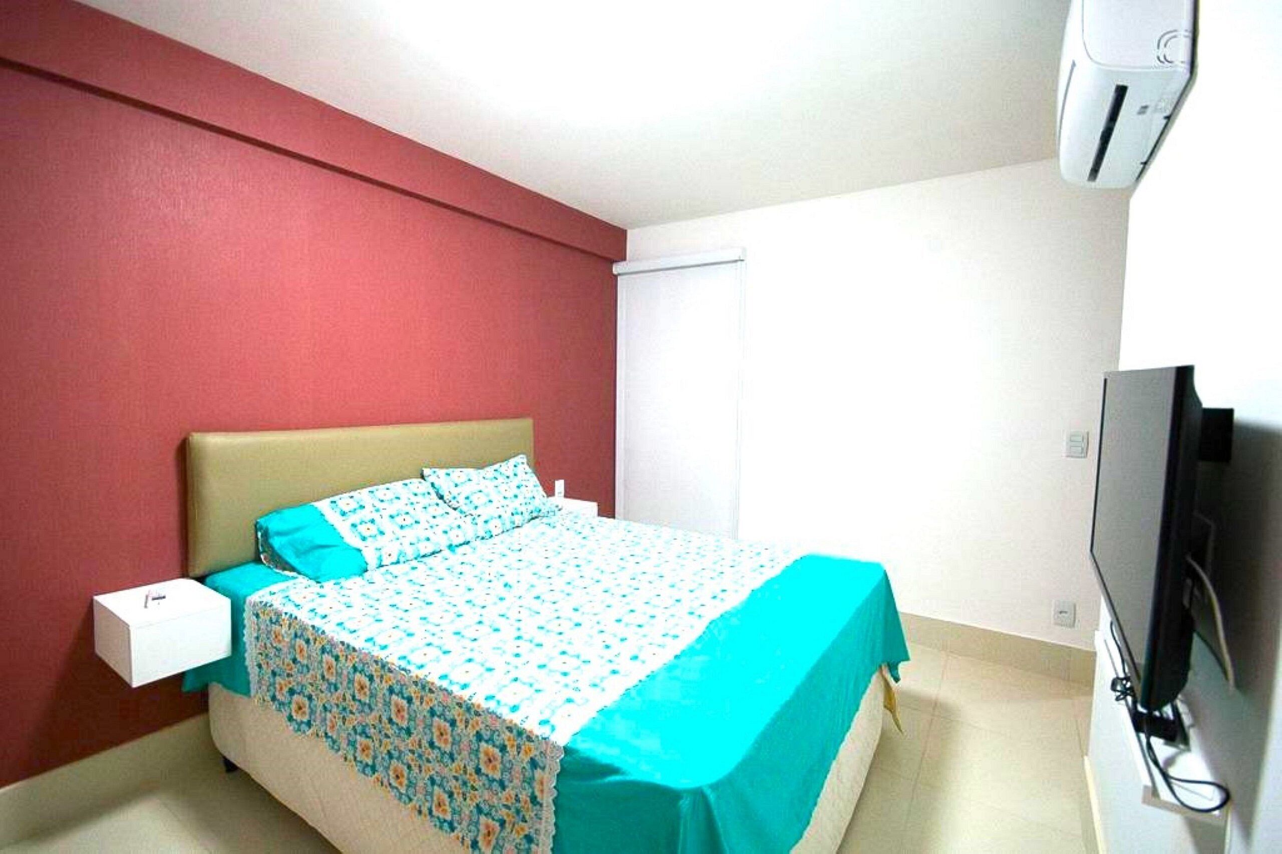 Een hotelkamer met een bed, een televisie en een airconditioning.