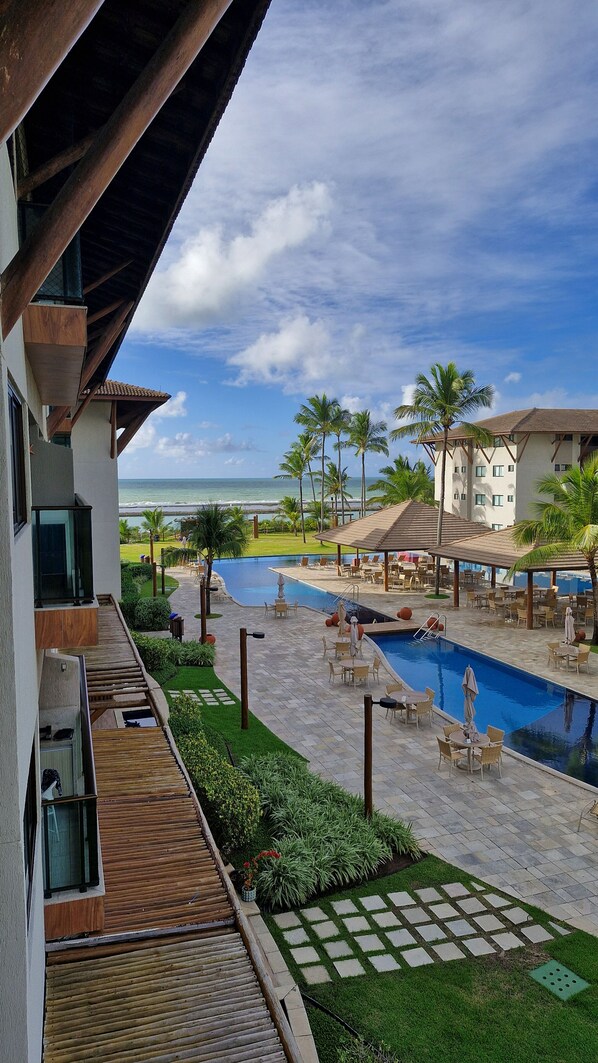 Un resort con piscina, mobiliario exterior y vista al océano.