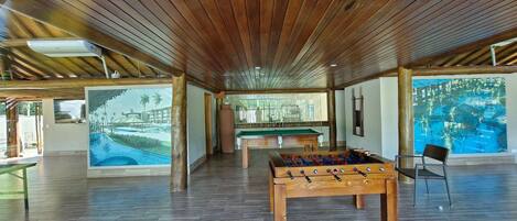 A spacious indoor area with a pool table, foosball table, and a billiards table.