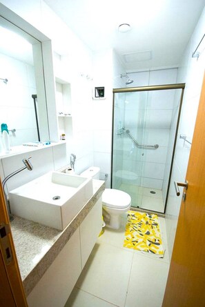 Een kleine badkamer met wastafel, toilet en douchecabine.