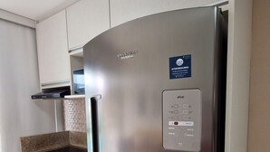 Departamento Deluxe | Cocina privada | Refrigerador con congelador, microondas, utensilios de cocina y comedor 