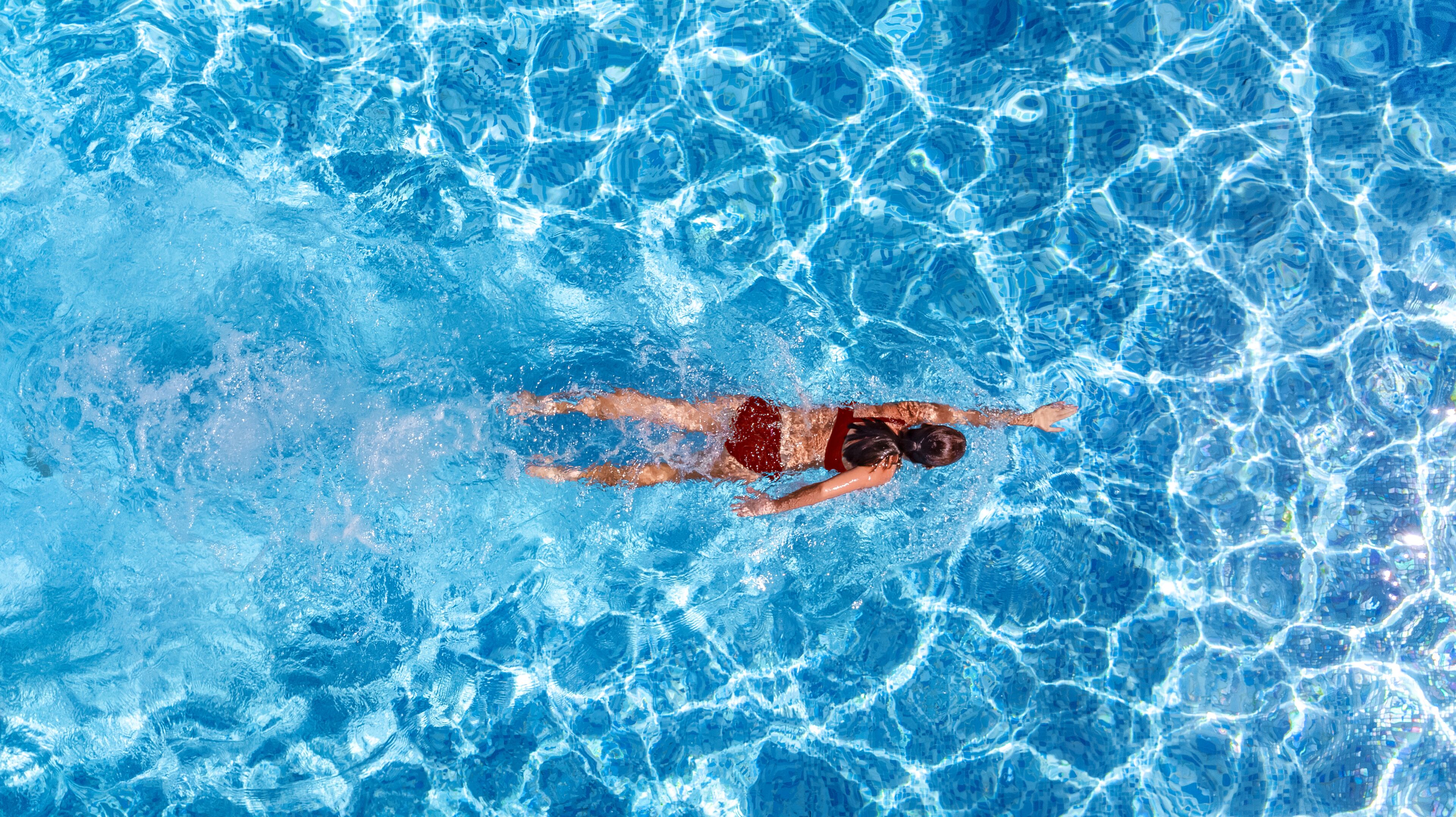 A person swimming in a pool with clear blue water.