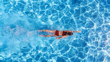 A person swimming in a pool with clear blue water.