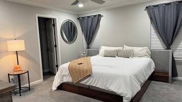 A bedroom with a bed, bedside tables, a ceiling fan, a lamp, and a door.