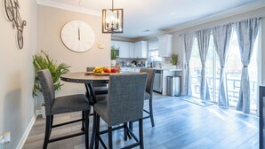A modern kitchen with white cabinets, a dining area with a round table and four chairs, and a large wall clock. - Charming 3-bedroom house with AC, WiFi in terrific Lithia Springs (Lithia Springs)