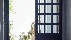An open door leading to a room with a view of trees and a building in the background. - Villa Antonella, app. Victory (Tavernerio)