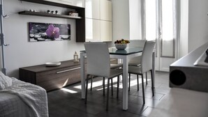 A modern kitchen with white cabinets, a dining table with chairs, a bowl of fruit, and a painting on the wall. - Villa Antonella, app. Victory (Tavernerio)