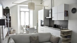A modern, minimalist living room with a sofa and a dining area in the background. - Villa Antonella, app. Victory (Tavernerio)