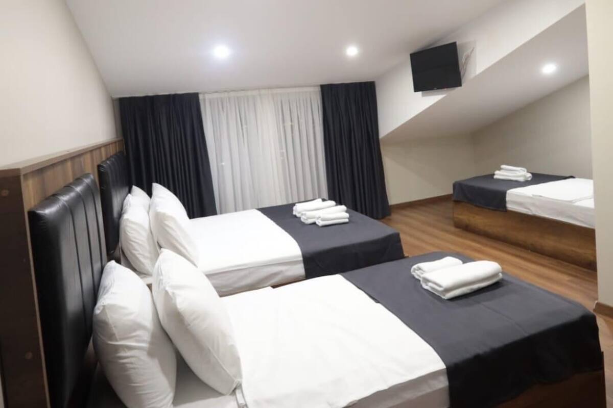 A hotel room with two beds, a flat-screen TV mounted on the wall, and a ceiling with recessed lighting.