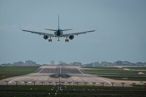 An airplane landing on a runway with buildings in the background. - BZN AİRPORT HOTEL (Arnavutköy)