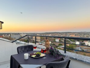 A balcony table with a plate of fruits, two glasses of red wine, and a decorative vase. - BZN AİRPORT HOTEL (Arnavutköy)