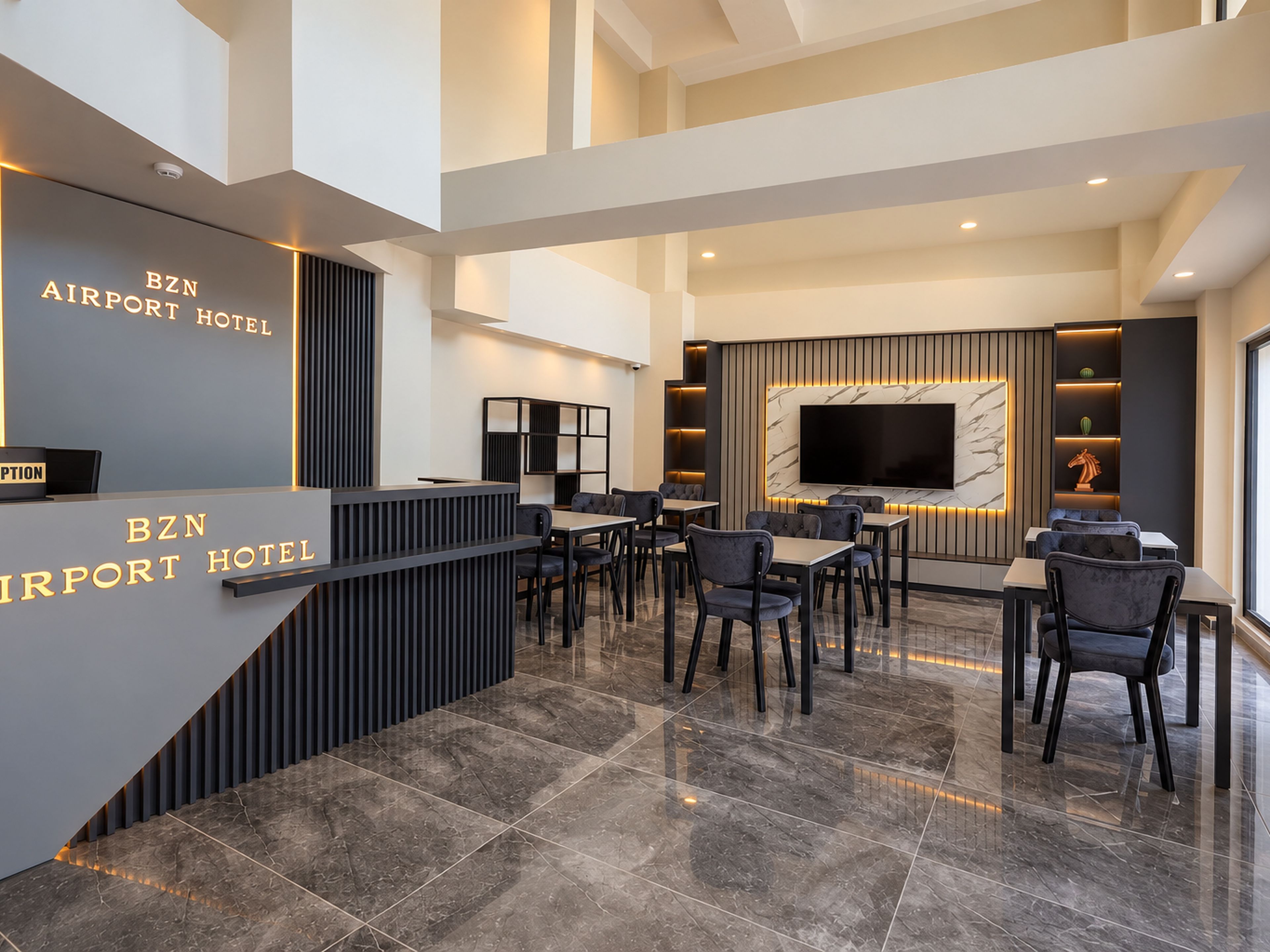 Empfangsbereich des BZN Airport Hotels mit modernem Design, inklusive einer Rezeption, einer Sitzecke und einem großen Bildschirm.