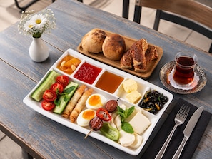 A table with a variety of food items including bread, dips, vegetables, and a glass of tea. - BZN AİRPORT HOTEL (Arnavutköy)
