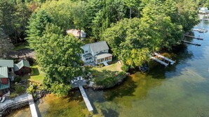 A lakeside property with a dock, a house, and a boat. - Point Comfort On Lake Winnisquam (Sanbornton)
