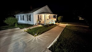 Una casa con un porche cubierto y un camino de entrada bien iluminado.