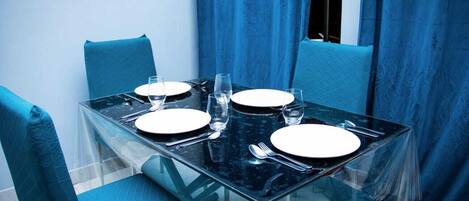 A dining table with four chairs, set for four people.