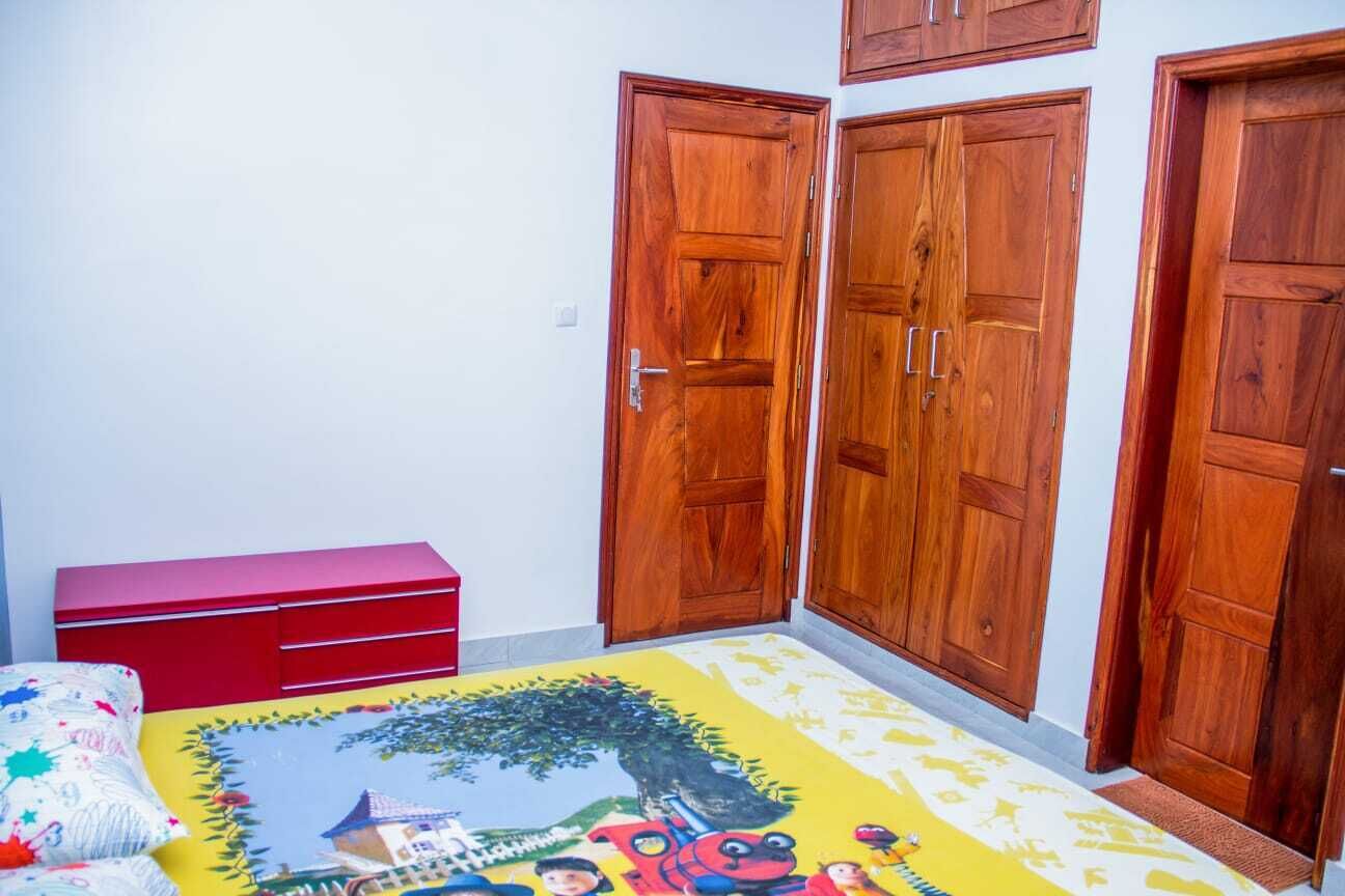 Une pièce dotée d’un tapis coloré représentant une scène de dessin animé, de placards en bois et d’un meuble de rangement rouge.