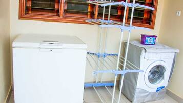 A compact laundry room with a white washing machine, a dryer, and a blue drying rack.