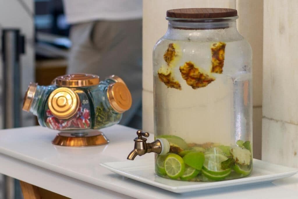 A glass jar with a metal lid containing lime slices and a decorative item with a copper-colored top.