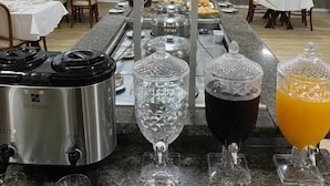 A buffet setup with a Hercules coffee maker, various glassware, and a juice dispenser. - Fast 10 City Hotel (Porto Alegre)