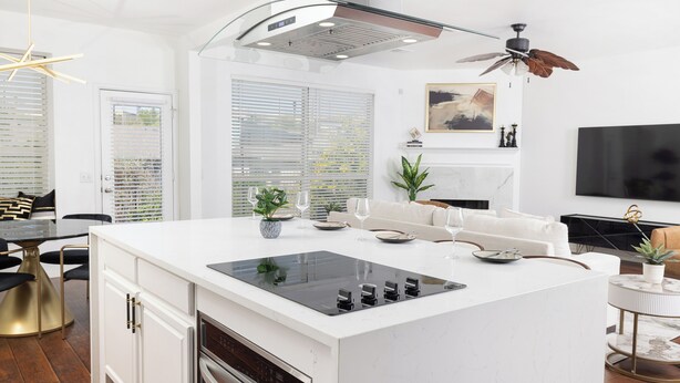 A modern kitchen with a central island, built-in oven, and a ceiling fan.