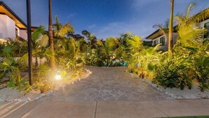 A paved pathway leading to a modern house surrounded by lush tropical vegetation. - Casa Las Flores - Tropical Luxury Retreat Pinilla (Pinilla)