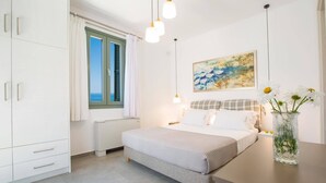 A bedroom with a bed, a nightstand, a dresser, a window with shutters, and a painting on the wall.