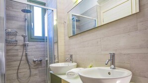 A modern bathroom with a glass-enclosed shower, two sinks, and a large mirror.