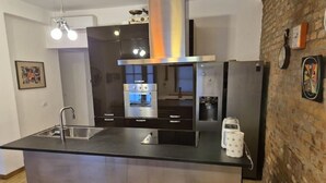 Une cuisine moderne dotée d’un îlot central, d’appareils électroménagers en acier inoxydable et d’un mur décoratif en briques.
