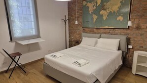 Une chambre à coucher avec un grand lit, une carte accrochée au mur, une fenêtre et un bureau.