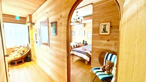 Ein Holzinterieur mit einem Bett, einem Sessel mit Teddybär und einem Fenster mit Blick.