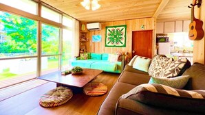 Ein gemütliches Wohnzimmer mit Holzboden, einem grünen Sofa, einem braunen Couchen und einem Esstisch.