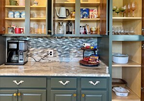 A kitchen with a coffee maker, a microwave, and a variety of kitchenware on shelves.