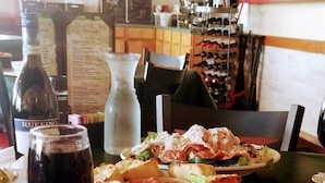 Un ambiente de restaurante con una pizarra de menú, una botella de vino y diferentes platos sobre la mesa.