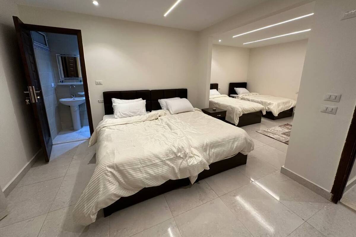 A modern bedroom with a large bed, a bedside table, and a mirror.