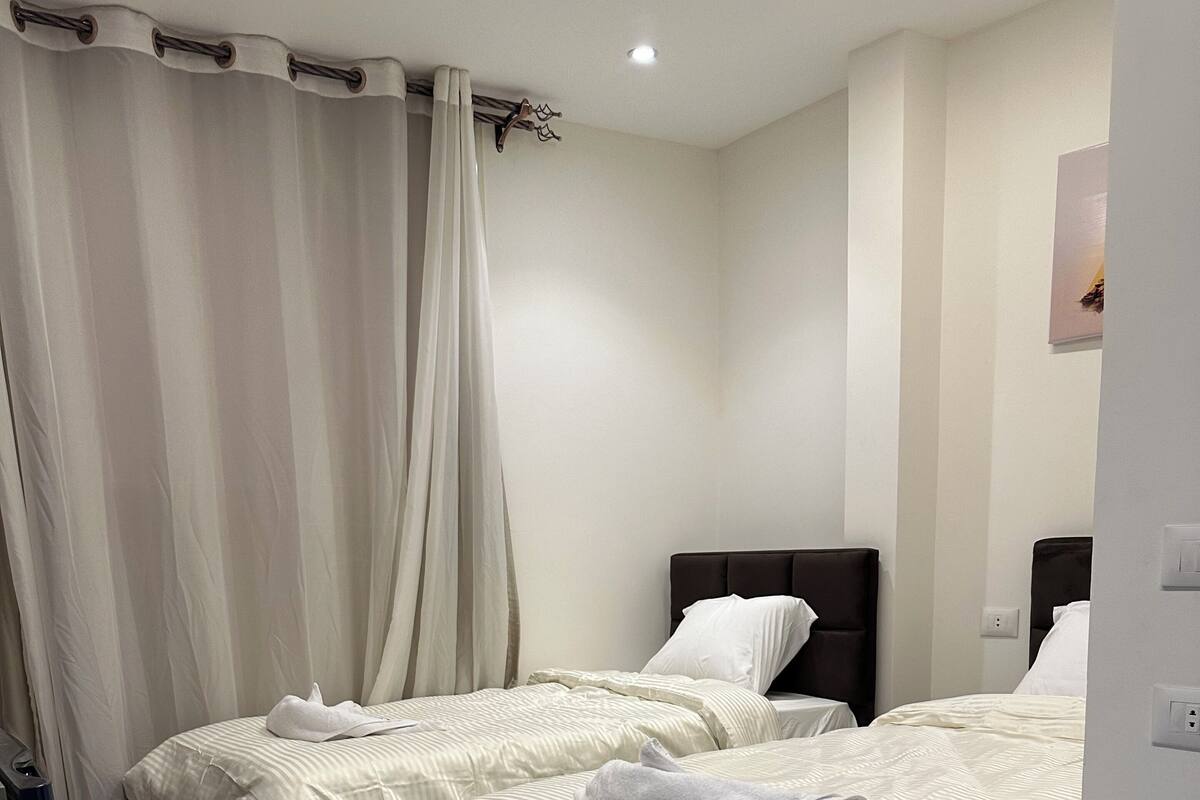 A hotel room with two beds, a bathroom, and a small sitting area.