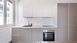 A modern kitchen with white cabinetry, a built-in oven, and a window providing natural light. - Bright apt. Duomo overview (Milano)