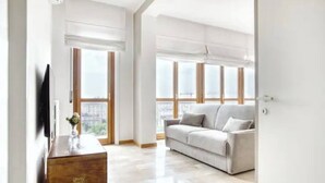 A spacious living room with a large window, a sofa, and a wooden coffee table. - Bright apt. Duomo overview (Milano)