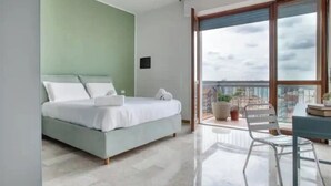 A modern bedroom with a bed, a small table, and a chair. - Bright apt. Duomo overview (Milano)