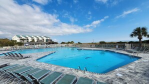 Une grande piscine avec plusieurs couloirs de nage, entourée de chaises longues et dotée d’une terrasse carrelée.